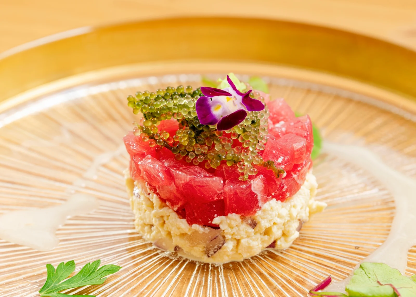 ガラスの皿に盛り付けた海ぶどうとマグロの料理